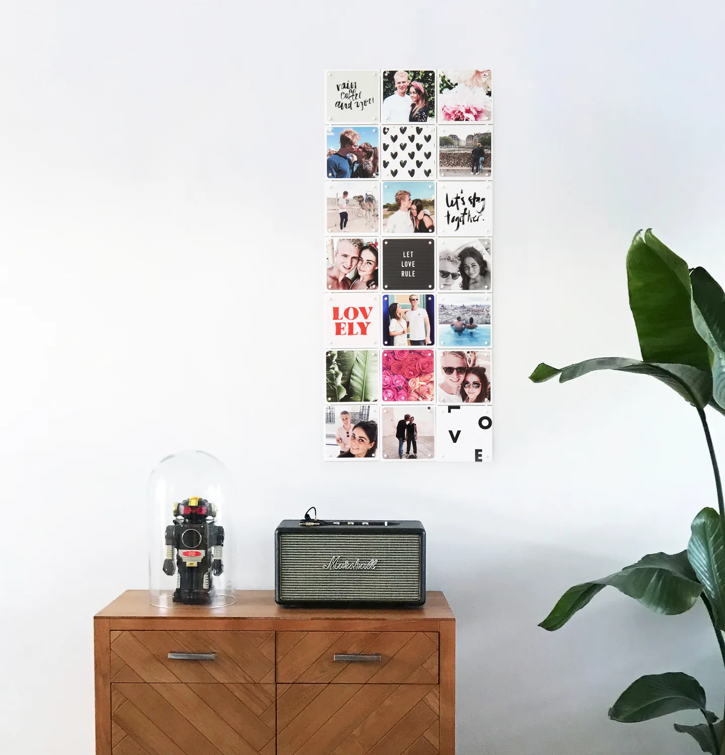 Narrow photo collage IXXI of a couple’s own photos, quotes and flowers on a white wall above a wooden sideboard