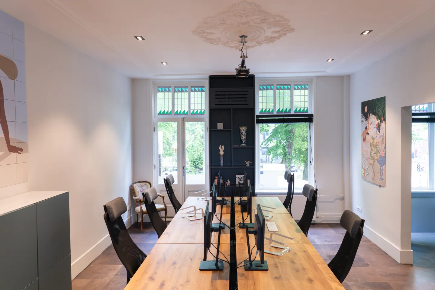 De lange werktafel onder het ornamentplafond van het monumentale pand
